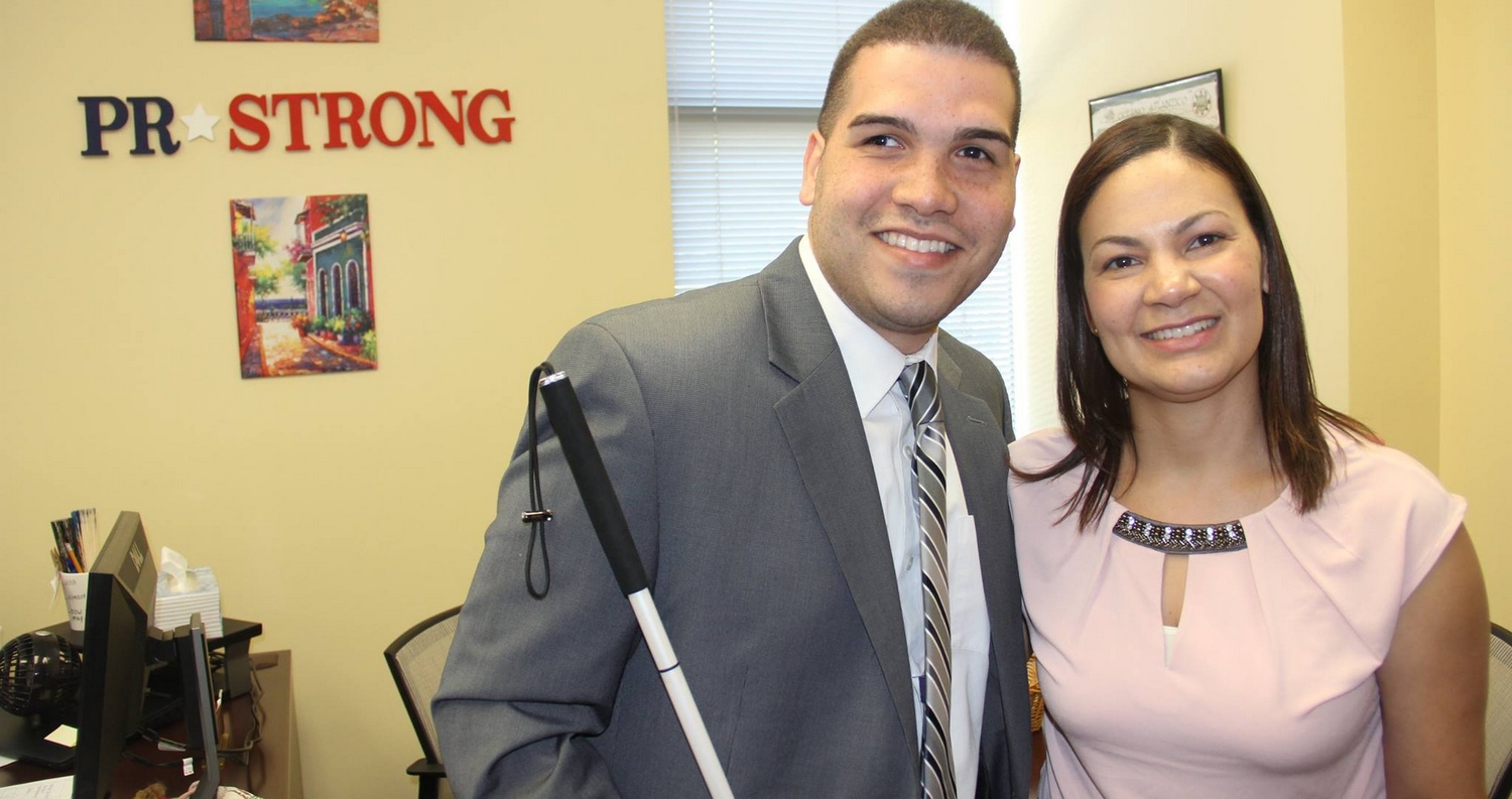Paul Martinez and Mireya Hernandez standing and smiling in Mireya's office.